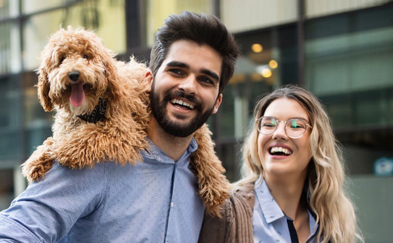 Young couple walking in a downtown area with their dog